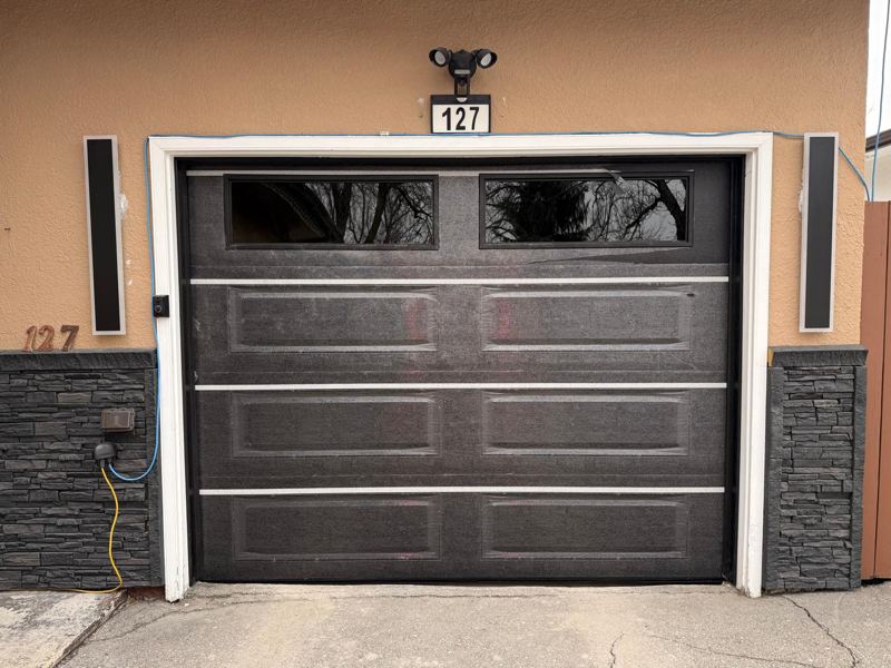 Black long-panel garage door with a row of top windows