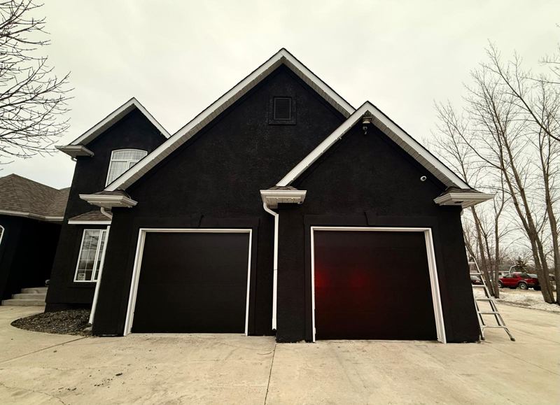 Two black garage doors on a dark detached garage