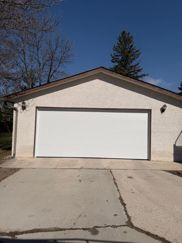 White garage door on a detached stucco garage