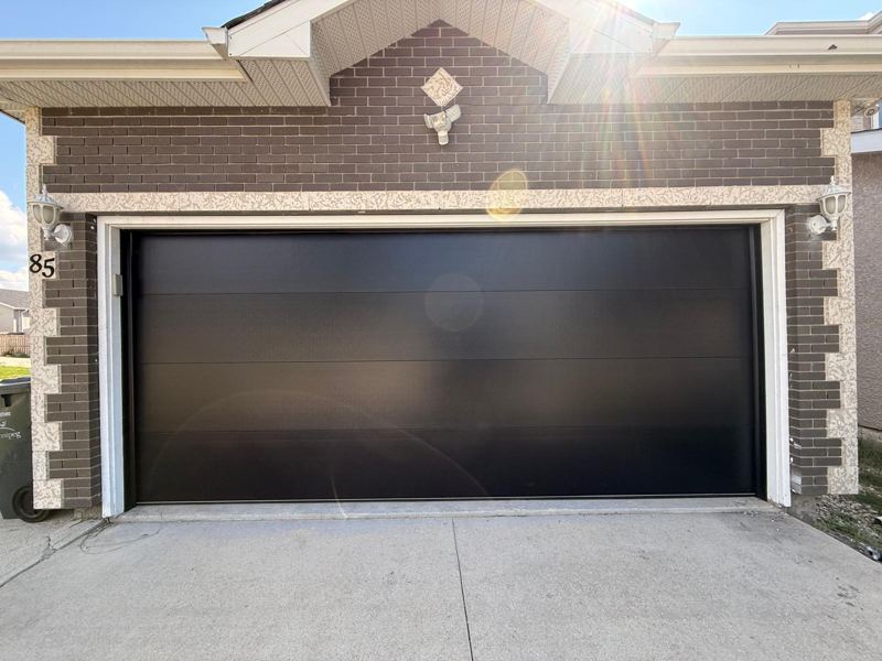 Black flush double garage door on a brick home