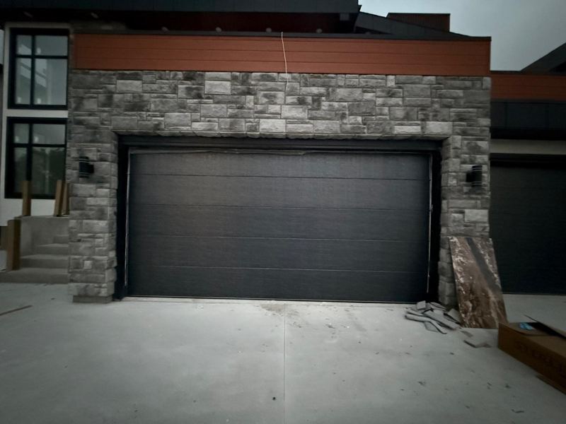 Charcoal double garage door on a stone-clad home
