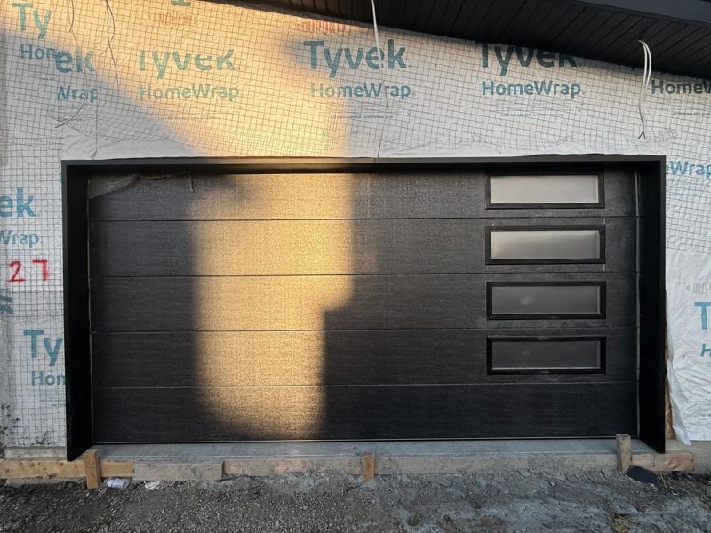 Black garage door with side windows on new construction